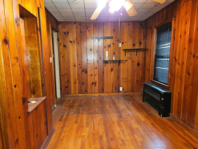 unfurnished room with hardwood / wood-style flooring, ceiling fan, and wood walls