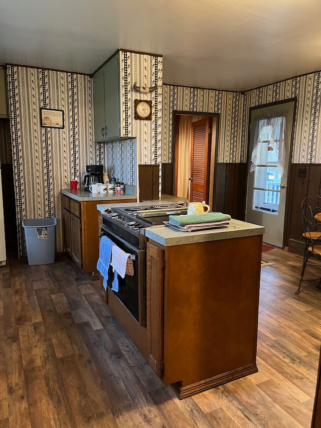 5721 N Rossman Rd W, Kingston, MI 48741 - kitchen featuring range with gas cooktop, dark wood-style flooring, wallpapered walls, light countertops, and brown cabinets