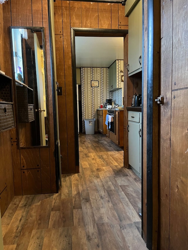 hall with wood walls and dark wood-type flooring