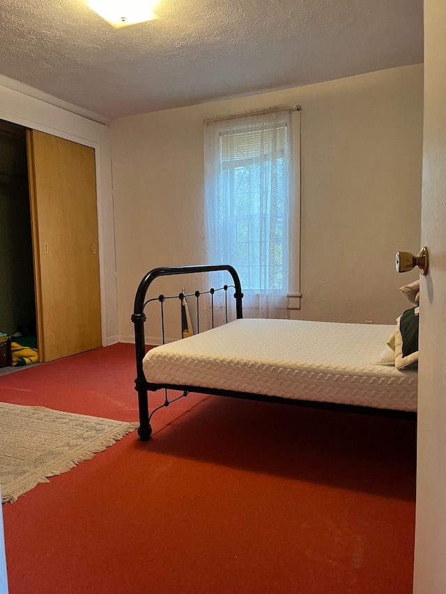 bedroom with a closet, carpet floors, and a textured ceiling