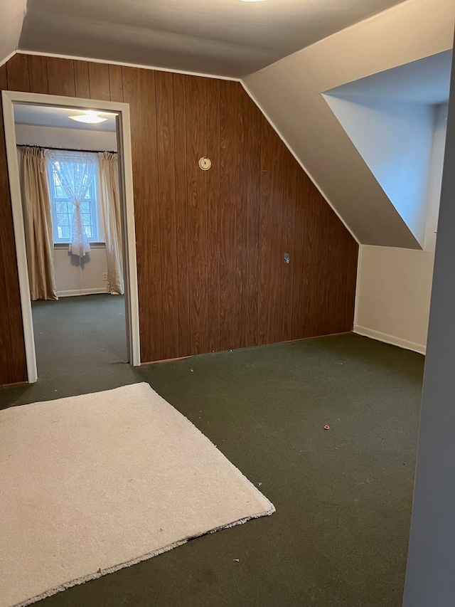 bonus room with wood walls, lofted ceiling, and dark carpet