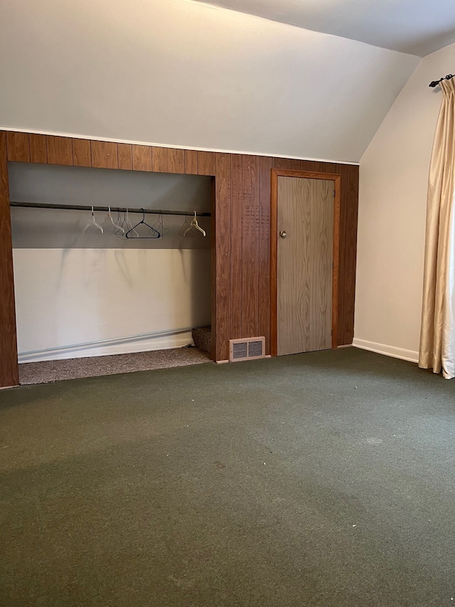 unfurnished bedroom with carpet, a closet, and vaulted ceiling