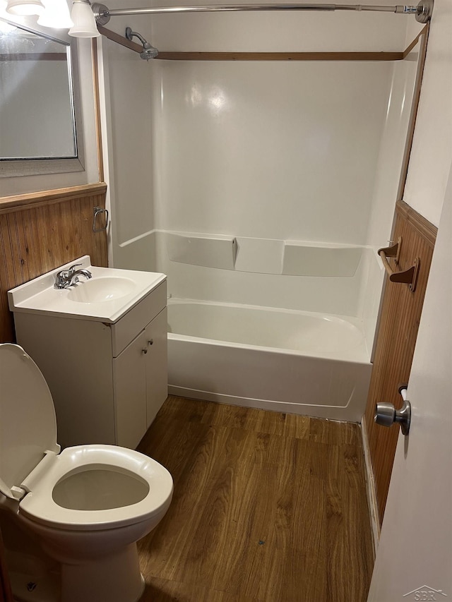 full bathroom featuring bathtub / shower combination, vanity, wood-type flooring, toilet, and wood walls