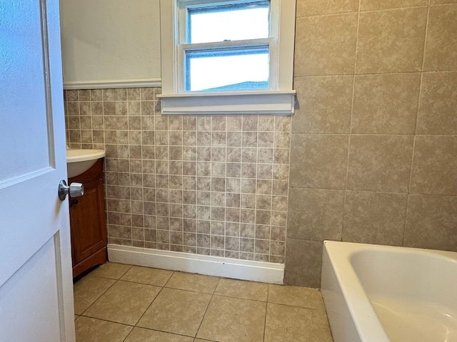 bathroom featuring tile patterned floors, a tub, vanity, and tile walls