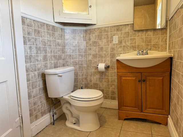 bathroom featuring toilet, vanity, tile patterned floors, and tile walls