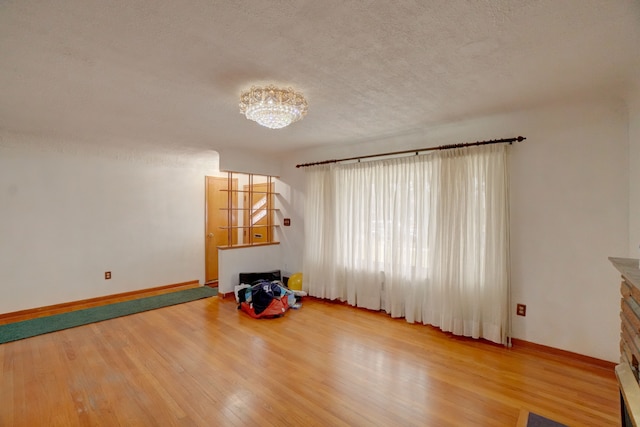 interior space with a fireplace, hardwood / wood-style floors, a textured ceiling, and a notable chandelier