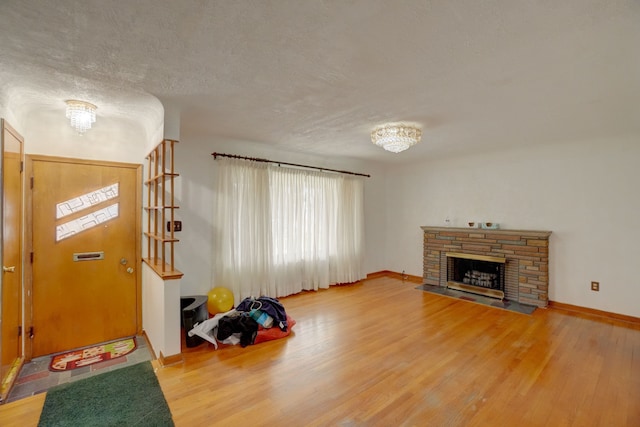 entrance foyer with a stone fireplace, wood-type flooring, and a textured ceiling