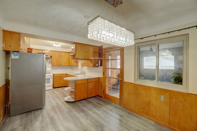 kitchen with kitchen peninsula, electric stove, a notable chandelier, light hardwood / wood-style floors, and stainless steel refrigerator