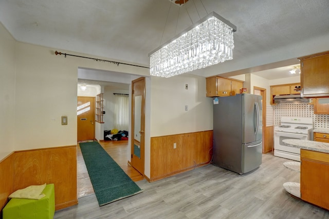 kitchen featuring white range, light hardwood / wood-style flooring, tasteful backsplash, a notable chandelier, and stainless steel refrigerator