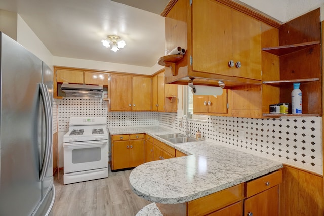 kitchen with white range, sink, decorative backsplash, stainless steel fridge, and light wood-type flooring