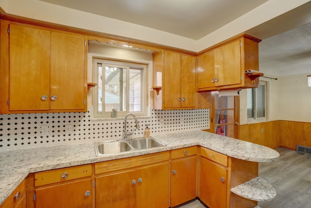 kitchen featuring kitchen peninsula, wood-type flooring, backsplash, and sink