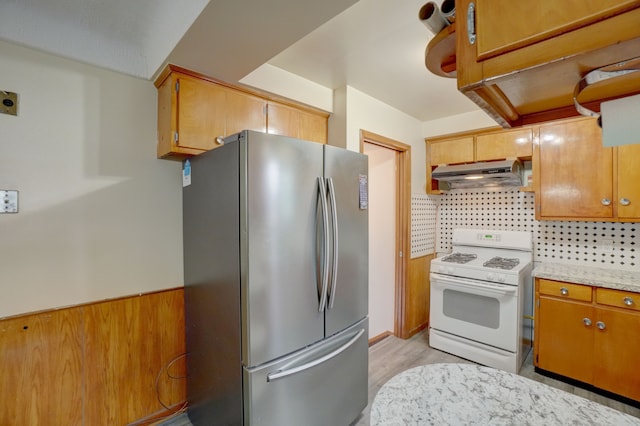 kitchen with stainless steel refrigerator, tasteful backsplash, light stone counters, light hardwood / wood-style flooring, and white range