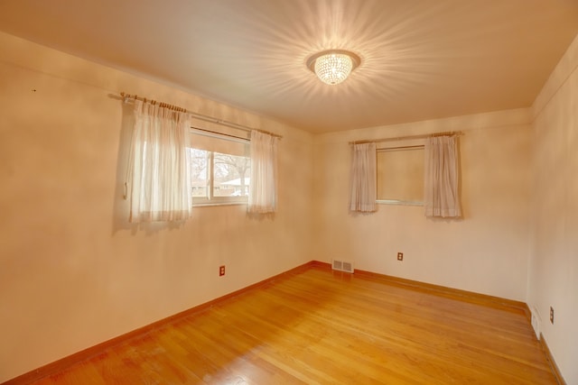 spare room featuring hardwood / wood-style floors and an inviting chandelier