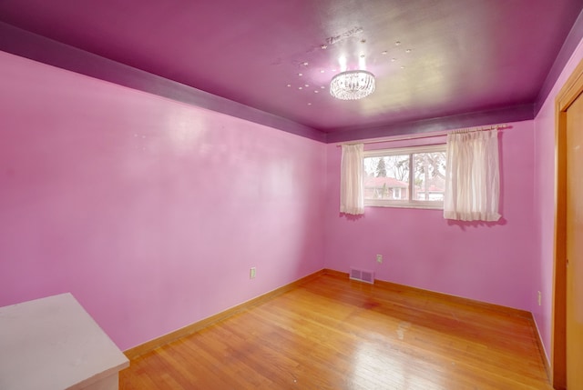 unfurnished room with hardwood / wood-style floors and a notable chandelier