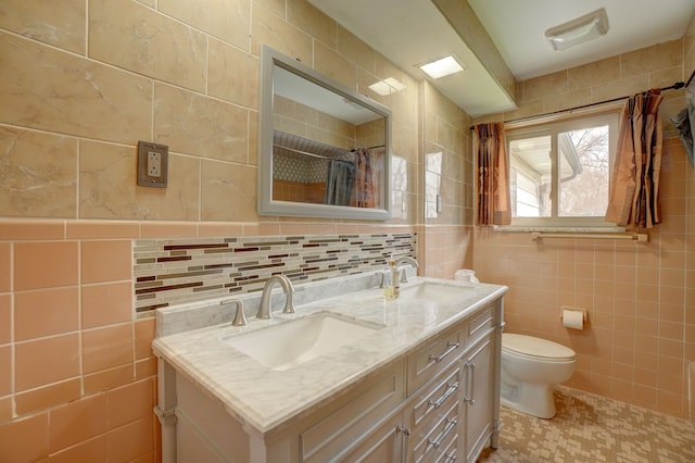 bathroom with vanity, toilet, and tile walls