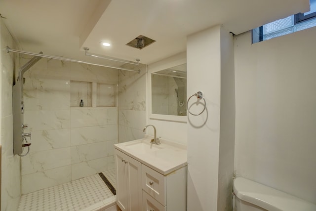 bathroom with tiled shower, vanity, and toilet