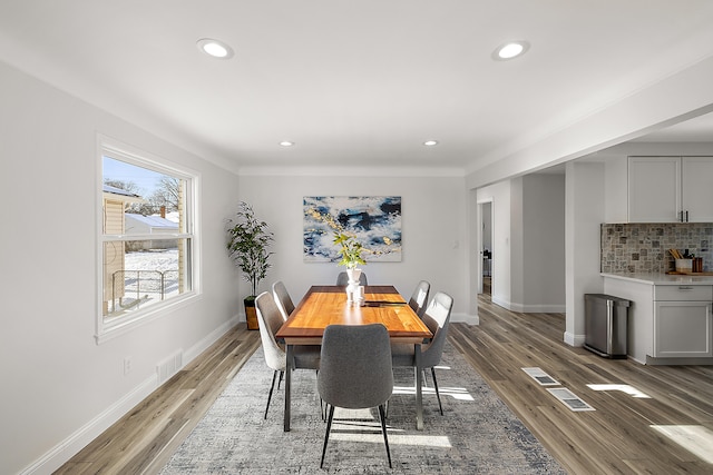 dining space with crown molding and light hardwood / wood-style flooring