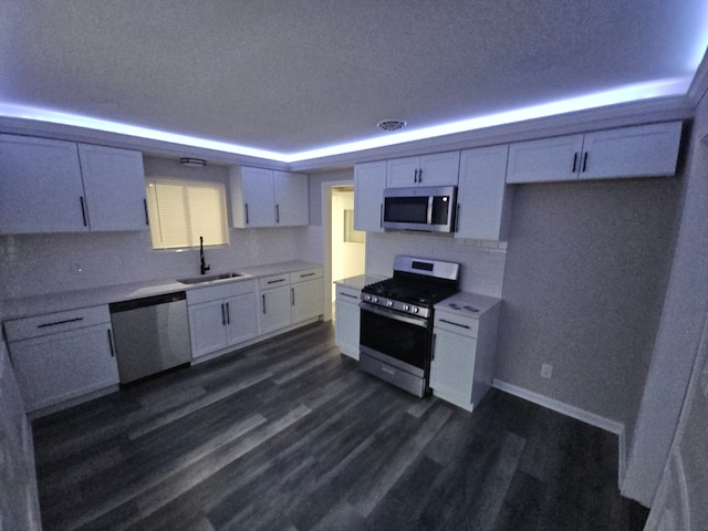 kitchen with white cabinets, sink, appliances with stainless steel finishes, tasteful backsplash, and dark hardwood / wood-style flooring