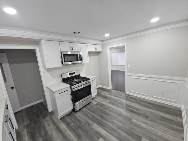 kitchen with white cabinets, appliances with stainless steel finishes, dark hardwood / wood-style flooring, and crown molding