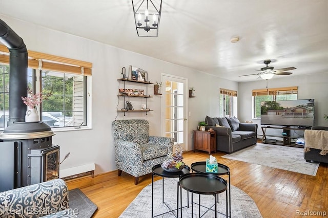 living room featuring a wood stove, plenty of natural light, and light wood-type flooring