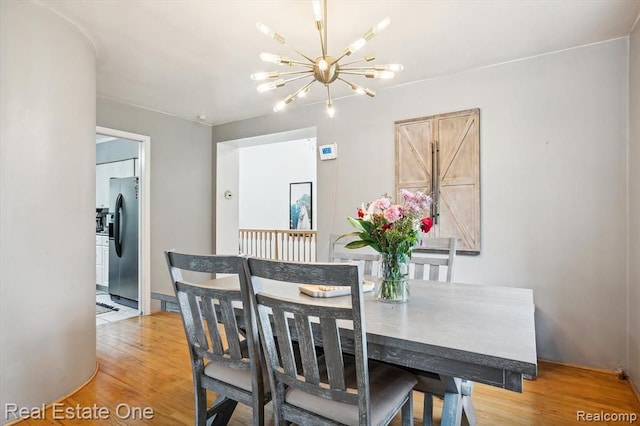 dining area with light hardwood / wood-style floors and a chandelier