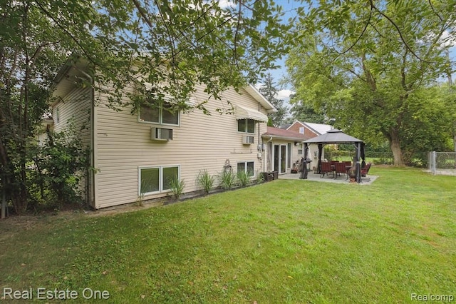 rear view of property featuring a gazebo, a wall unit AC, a patio, and a lawn