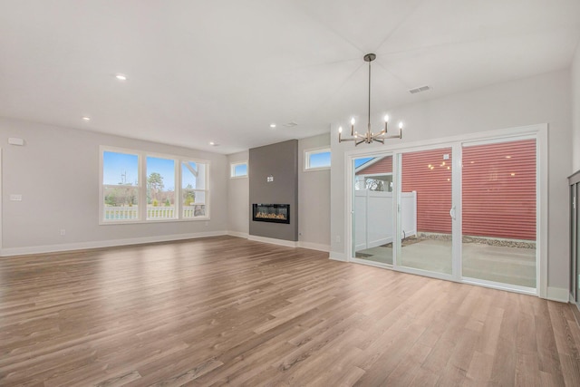 unfurnished living room with light wood-type flooring and a chandelier