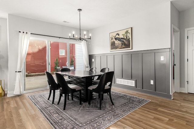 14236 Phoenix Pl, Holland, MI 49424 - dining room featuring a chandelier, light wood-style flooring, wainscoting, and a decorative wall