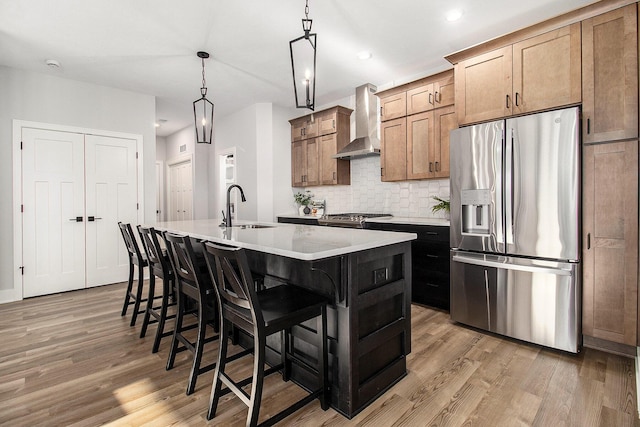 14236 Phoenix Pl, Holland, MI 49424 - kitchen with stainless steel fridge, wall chimney exhaust hood, a sink, a center island with sink, and light wood-style flooring
