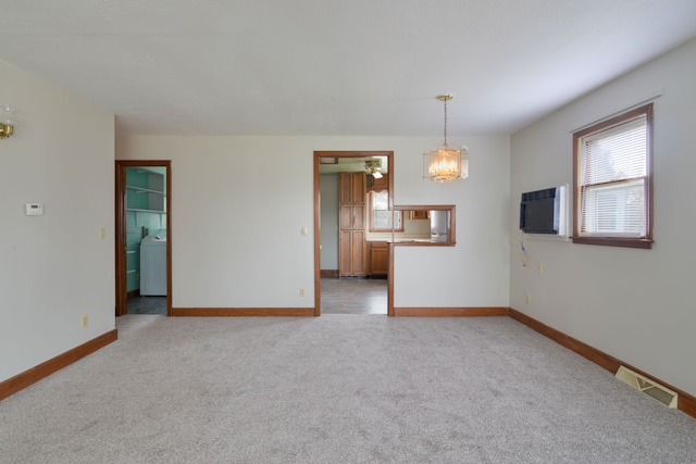 carpeted spare room featuring a chandelier, washer / clothes dryer, and a wall unit AC