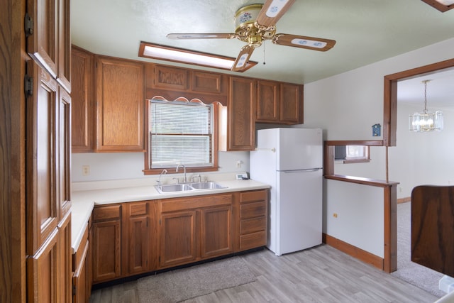 kitchen with sink, light hardwood / wood-style flooring, white fridge, decorative light fixtures, and ceiling fan with notable chandelier