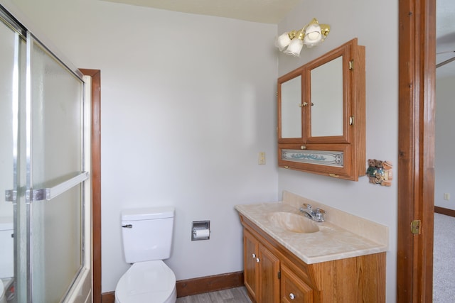 full bathroom with combined bath / shower with glass door, vanity, and toilet