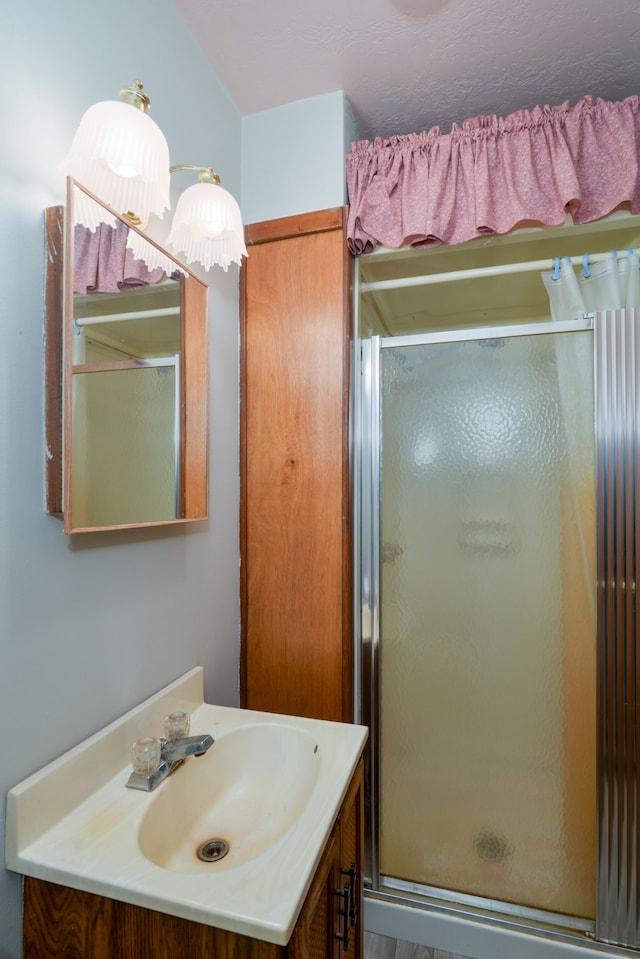 bathroom featuring a shower with door and vanity