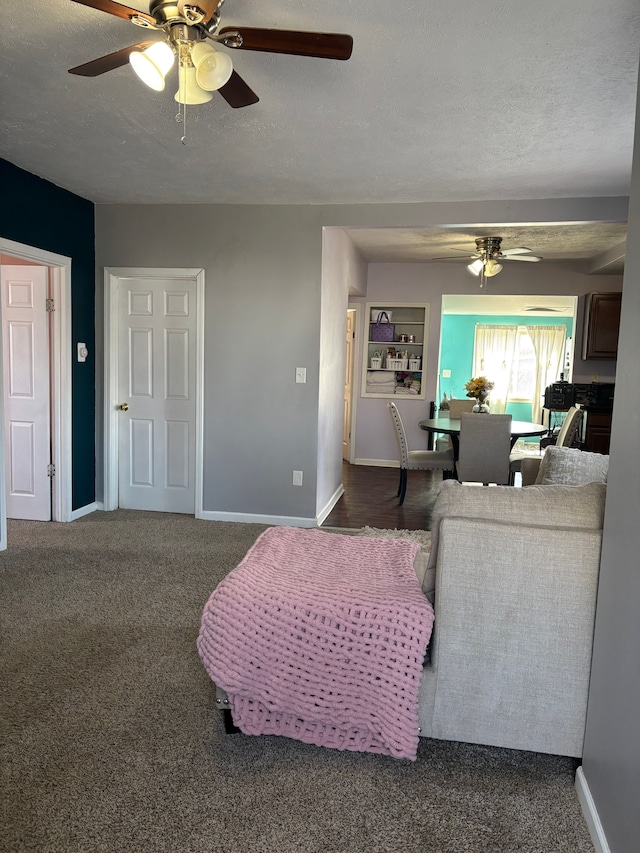 living room with baseboards, a ceiling fan, and a textured ceiling