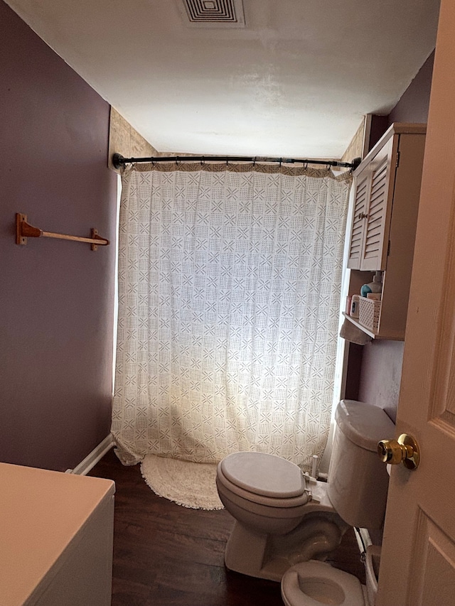bathroom with baseboards, visible vents, wood finished floors, and toilet