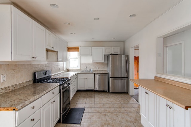 kitchen with tasteful backsplash, white cabinetry, sink, and appliances with stainless steel finishes