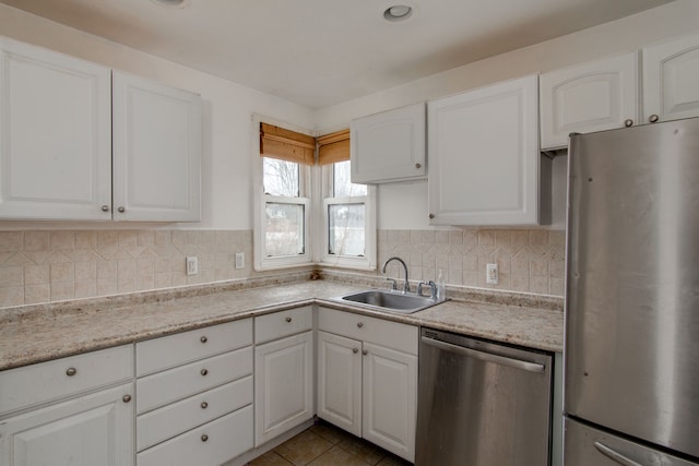 kitchen with backsplash, stainless steel appliances, white cabinetry, and sink