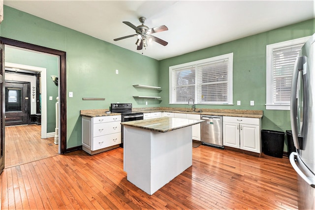 kitchen featuring white cabinets, light stone counters, light wood-type flooring, and appliances with stainless steel finishes