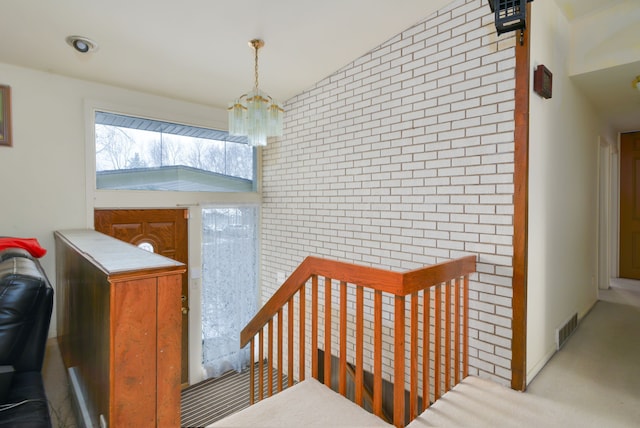 44080 Marlson Ave, Novi, MI 48375 - staircase with a chandelier, an accent wall, brick wall, and lofted ceiling