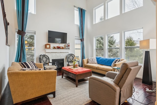 living room featuring hardwood / wood-style flooring, a healthy amount of sunlight, a towering ceiling, and a fireplace