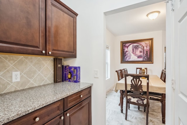 kitchen featuring tasteful backsplash, dark brown cabinetry, and light stone counters