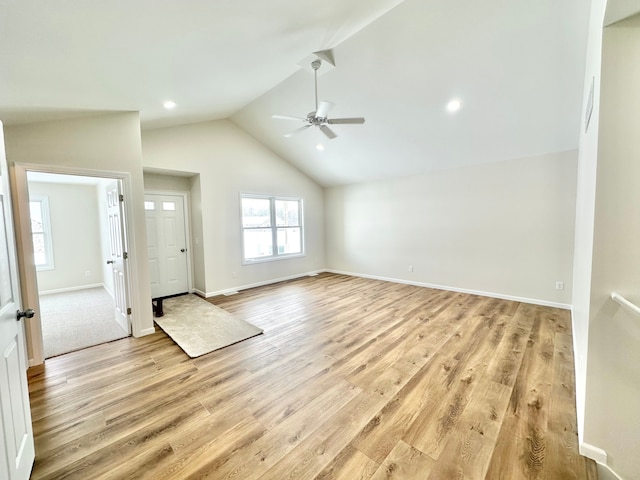 unfurnished living room with light wood-type flooring, a wealth of natural light, and lofted ceiling