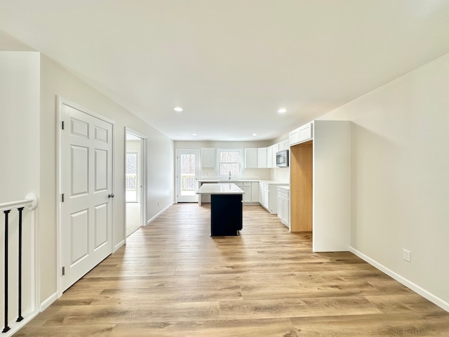 kitchen with a center island, light hardwood / wood-style floors, white cabinetry, and sink