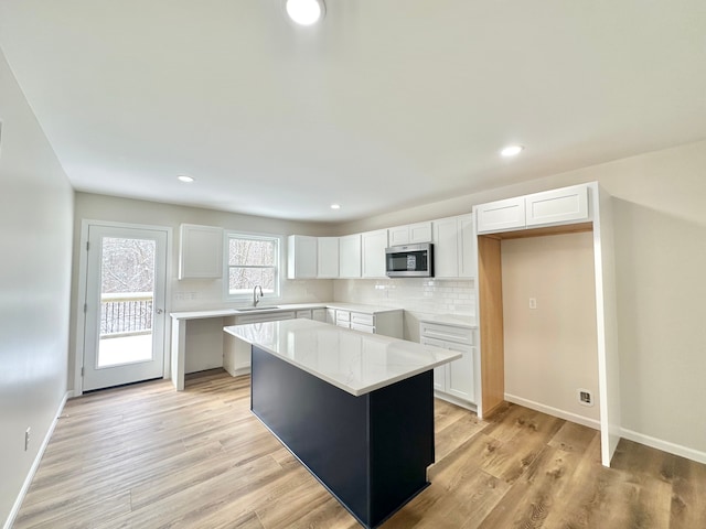 kitchen featuring white cabinets, decorative backsplash, a center island, and sink