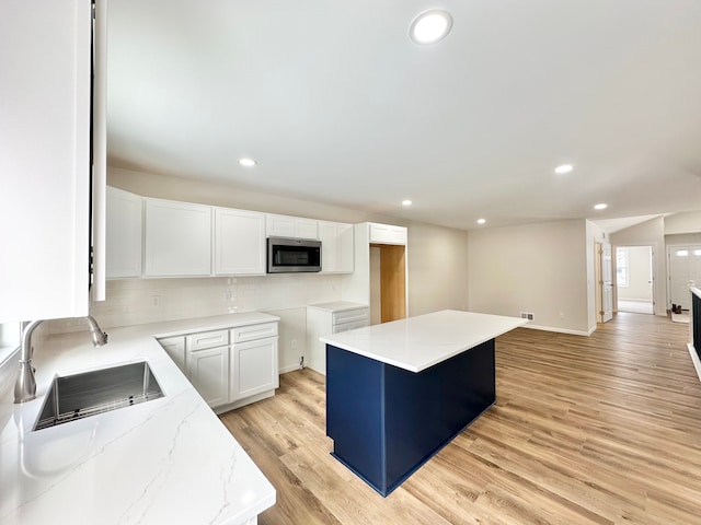 kitchen featuring a center island, sink, tasteful backsplash, light hardwood / wood-style flooring, and white cabinets