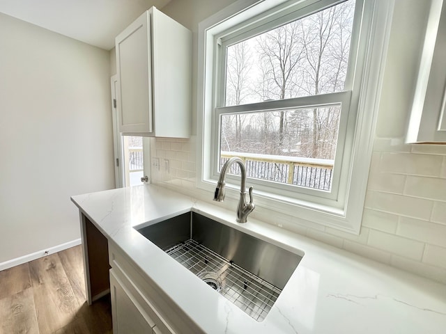 kitchen featuring light stone countertops, backsplash, sink, dark hardwood / wood-style floors, and white cabinetry