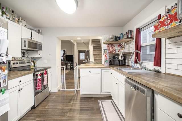 kitchen with white cabinets, wood counters, sink, and stainless steel appliances