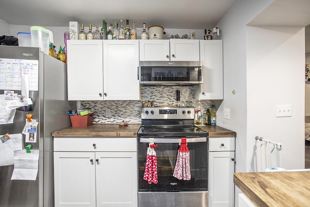 kitchen with wood counters, white cabinetry, appliances with stainless steel finishes, and tasteful backsplash