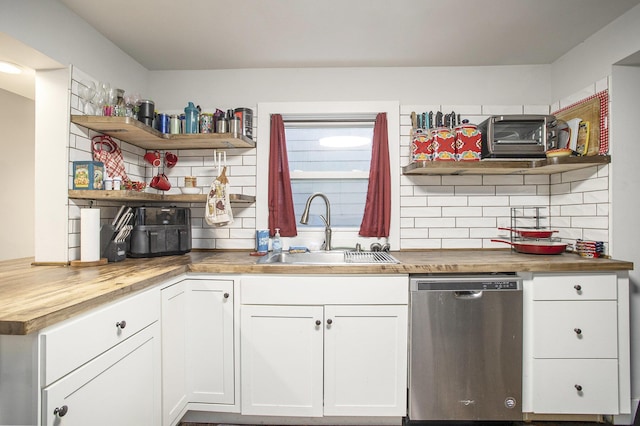 kitchen featuring white cabinetry, sink, stainless steel dishwasher, wooden counters, and decorative backsplash