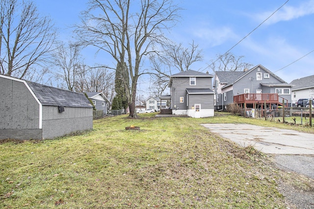 view of yard with a wooden deck, a fire pit, and a storage shed